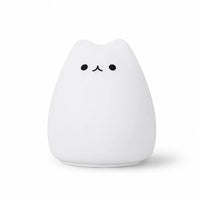 Veilleuse en silicone blanc en forme de petit chat arrondi au design épuré. Elle présente deux petits yeux ronds et un museau noir minimaliste, présentée de face sur un fond blanc uni.
