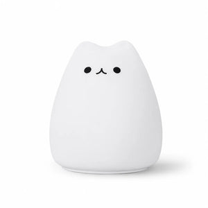 Veilleuse en silicone blanc en forme de petit chat arrondi au design épuré. Elle présente deux petits yeux ronds et un museau noir minimaliste, présentée de face sur un fond blanc uni.