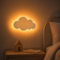 Applique murale nuage allumée fixée au-dessus d'une table de chevet diffusant un halo de lumière chaude