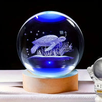 Boule de cristal gravée en 3d représentant une tortue marine éclairée par une lumière bleue sur socle en bois