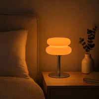 Lampe d'ambiance rétro en verre éclairée diffusant une lumière chaude orange sur une table de chevet dans une chambre