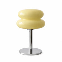 Lampe d'ambiance design en verre soufflé jaune pastel avec pied en métal chromé brillant sur fond blanc