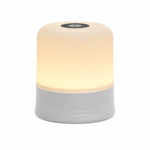 Lampe de chevet tactile au design cylindrique épuré, dotée d'une base grise et d'un diffuseur supérieur blanc allumé émettant une lueur chaude, avec un bouton de contrôle circulaire noir sur le dessus, présentée de face sur fond blanc.