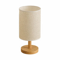 Lampe de chevet minimaliste avec socle en bois clair et abat-jour cylindrique en tissu crème sur fond blanc