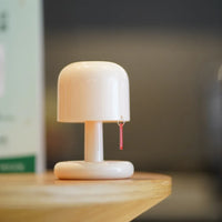Lampe de chevet nomade beige au design champignon posée sur le bord d'une table en bois