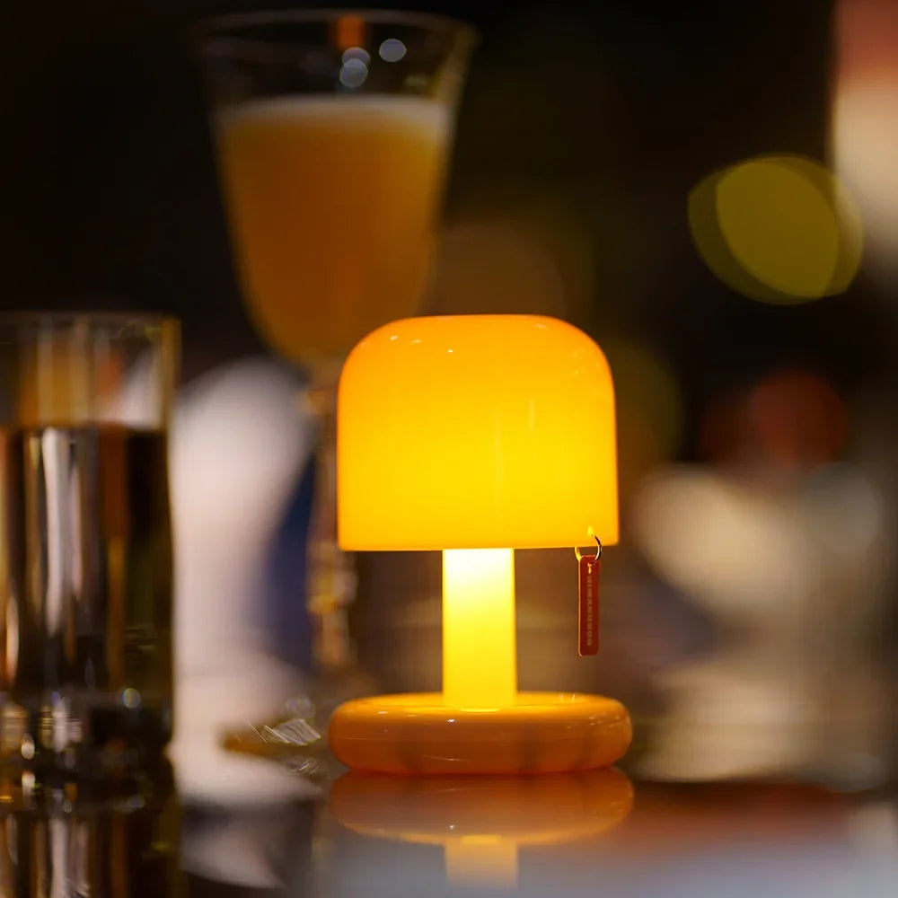 Lampe de chevet nomade champignon allumée diffusant une lumière jaune chaleureuse sur une table de soirée