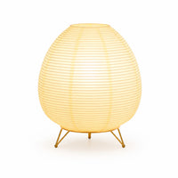 Lampe lanterne japonaise en papier de forme ovale allumée sur un trépied en métal doré.