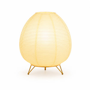 Lampe lanterne japonaise en papier de forme ovale allumée sur un trépied en métal doré.