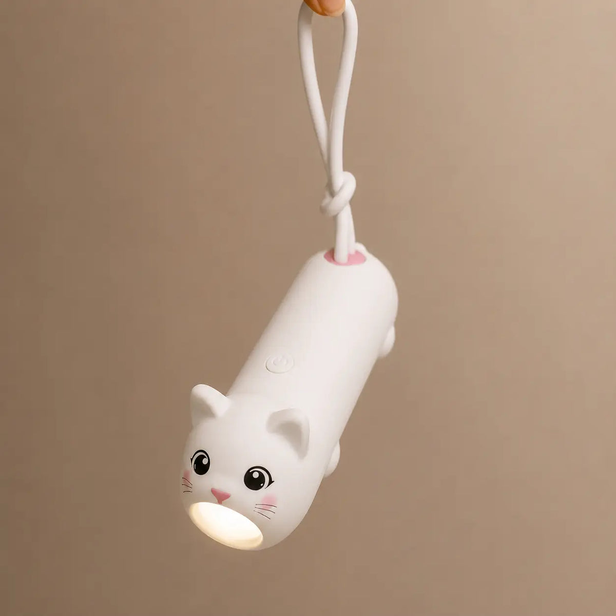 Lampe torche en forme de chat blanc suspendue par son attache en silicone, éclairant vers le bas.