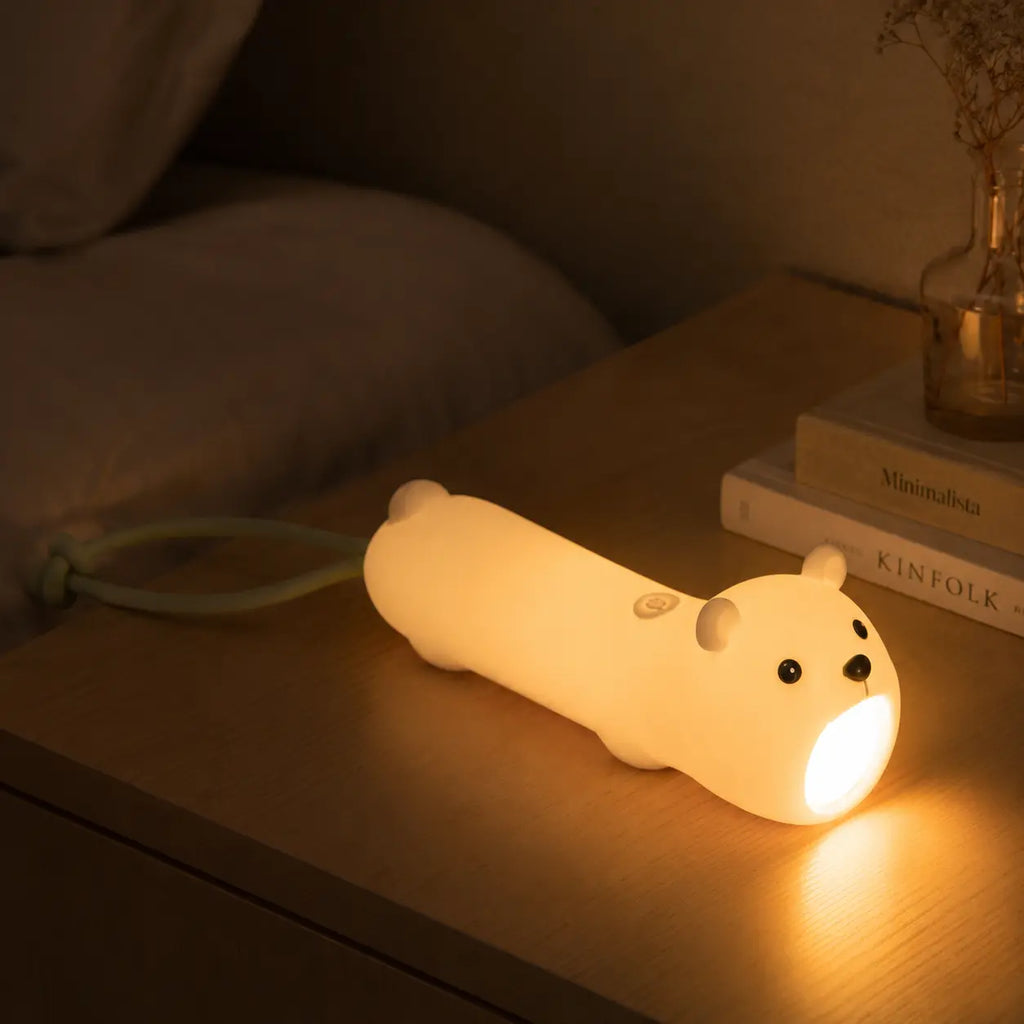 Lampe torche en forme d'ours blanc éclairant une table de chevet dans l'obscurité.
