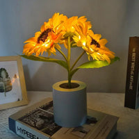 Lampe fleur tournesol led allumée posée dans un pot cylindrique sur une table de nuit