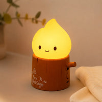 Lampe veilleuse flamme allumée en forme de personnage souriant sur une bûche en bois.