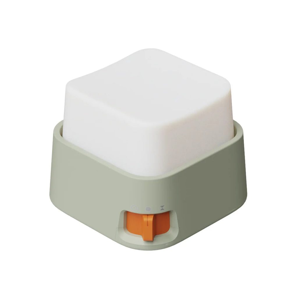 Mini veilleuse anti-stress cubique blanche avec base vert sauge et interrupteur orange sur fond blanc