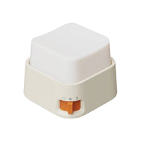 Mini veilleuse anti-stress cubique blanche avec base beige et interrupteur orange sur fond blanc