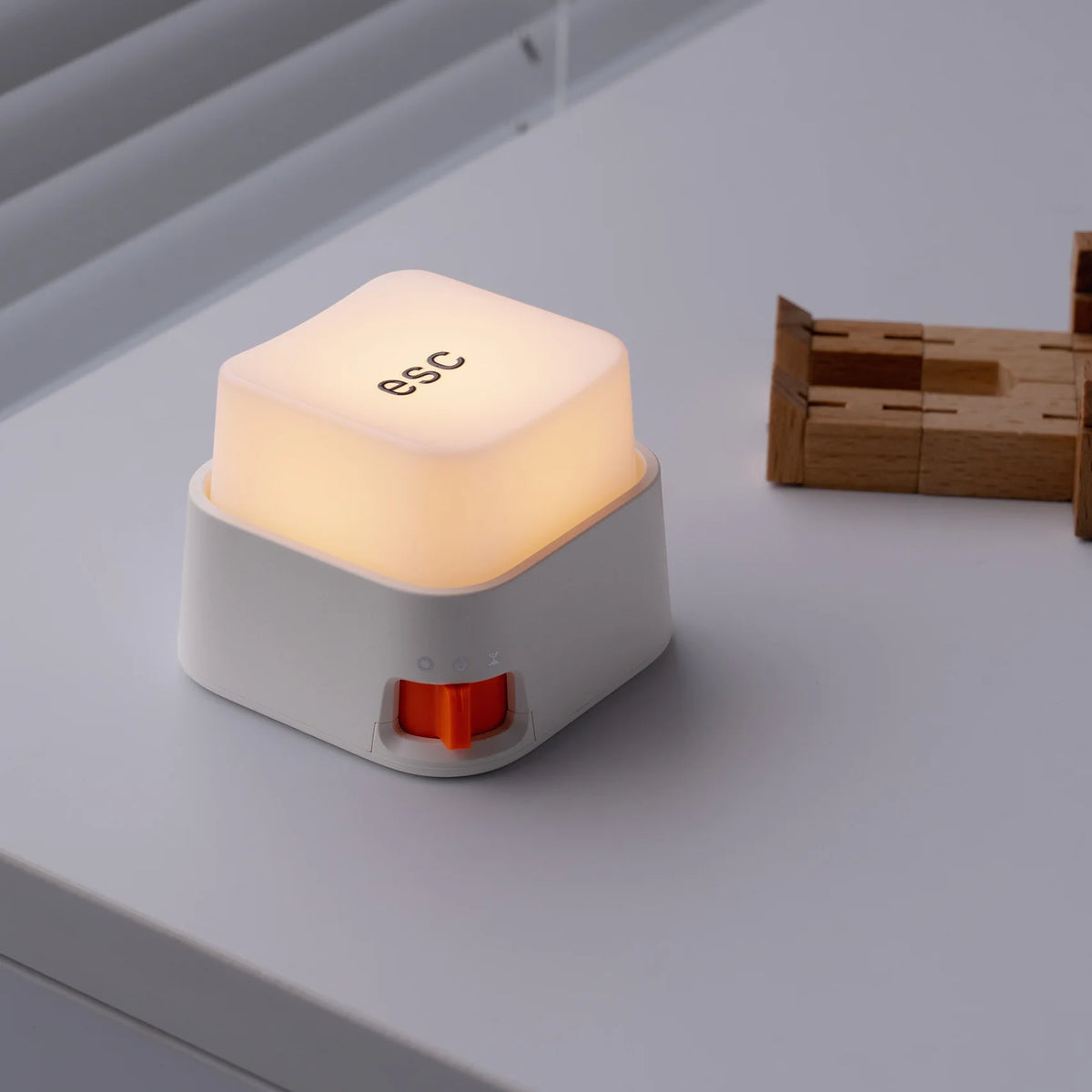 Mini veilleuse anti-stress en forme de touche ESC allumée d'une lumière chaude posée sur un bureau