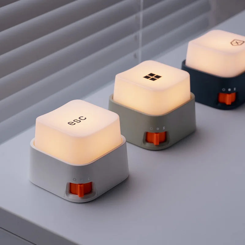 Trois mini veilleuses anti-stress en forme de touches de clavier éclairées alignées sur un bureau