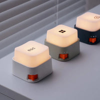 Trois mini veilleuses anti-stress en forme de touches de clavier éclairées alignées sur un bureau