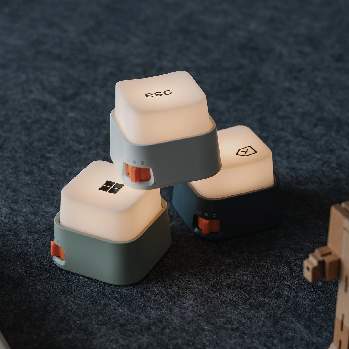 Trois mini veilleuses anti-stress en forme de touches de clavier éclairées posées sur une surface en feutre