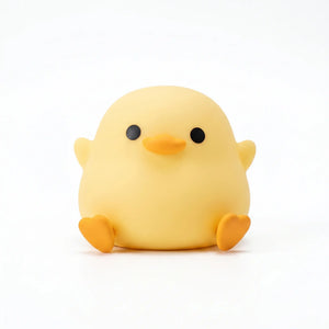 Petite veilleuse canard jaune en silicone au design kawaii avec bec et pattes oranges, posée sur fond blanc.