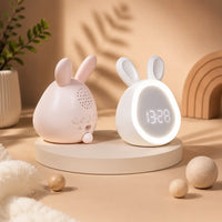 Réveils lapins LED rose et blanc disposés sur un socle beige dans un décor doux avec de petits objets en bois.