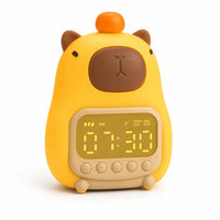 Réveil veilleuse capybara jaune avec une petite orange sur la tête et un écran numérique affichant l'heure sur fond blanc.
