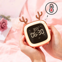 Réveil de chevet bois de cerf corail tenu dans les mains affichant la température de la pièce avec un pictogramme thermomètre.