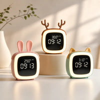 Trois réveils veilleuses de chevet allumés avec des formes d'oreilles de lapin rose, de bois de cerf corail et d'oreilles classiques vert d'eau dans un décor épuré.