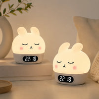Deux réveils veilleuses lapin aux yeux clos et joues roses allumés, disposés dans un décor doux et épuré.