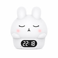 Réveil veilleuse lapin blanc aux yeux clos et petites joues roses avec affichage numérique de l'heure sur fond blanc.