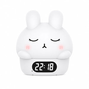 Réveil veilleuse lapin blanc aux yeux clos et petites joues roses avec affichage numérique de l'heure sur fond blanc.