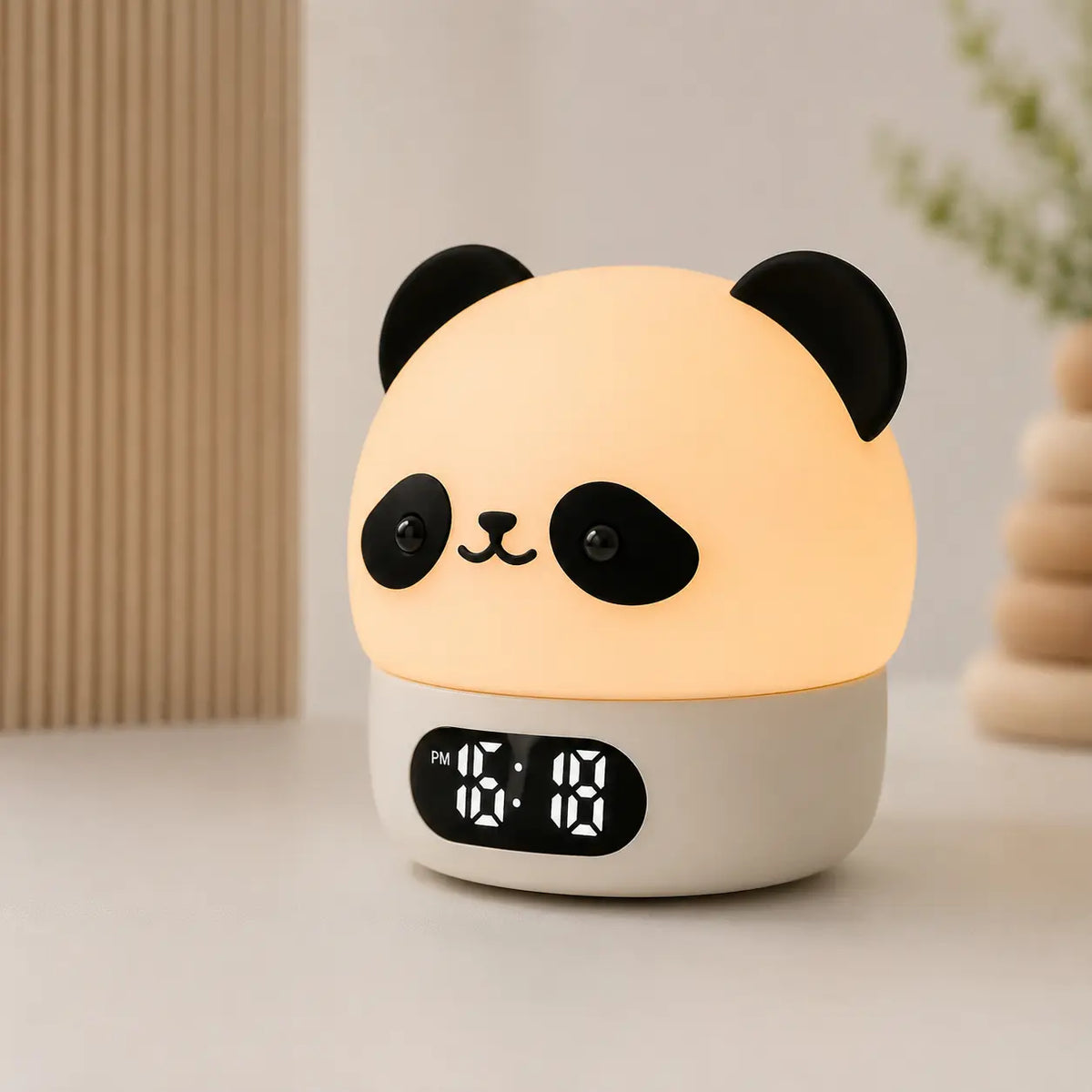 Réveil veilleuse panda allumé posé sur une table blanche dans un décor doux et épuré.