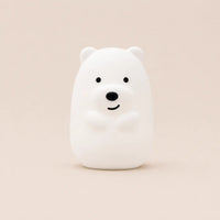 Veilleuse en silicone en forme d'ours blanc souriant, vue de face sur un fond beige neutre.