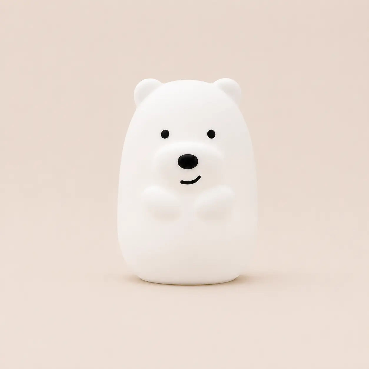 Veilleuse en silicone en forme d'ours blanc souriant, vue de face sur un fond beige neutre.