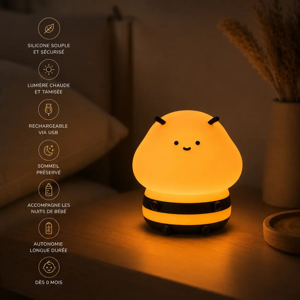 Infographie en français d'une veilleuse en silicone en forme de petite abeille souriante allumée sur une table de chevet en bois, listant ses points clés : silicone souple et sécurisé, lumière chaude et tamisée, rechargeable via USB, sommeil préservé, accompagne les nuits de bébé, autonomie longue durée et utilisable dès 0 mois.