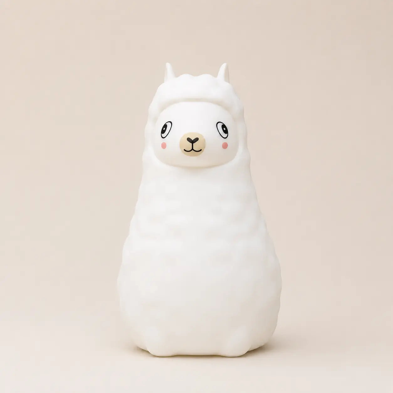 Veilleuse en silicone en forme de petit alpaga blanc, sur un fond beige neutre.