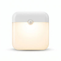 Veilleuse carrée blanche à capteur de mouvement allumée avec lumière chaude sur fond blanc