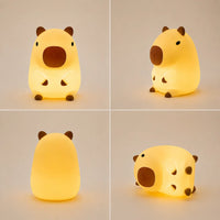 Planche produit de la veilleuse capybara en silicone allumée sous quatre angles différents : de face, de trois-quarts, de dos et couchée sur le côté, illustrant sa diffusion de lumière chaude.