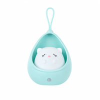 Veilleuse pour bébé éteinte représentant un petit chat blanc installé dans un cocon protecteur suspendu en silicone bleu menthe, présentée de face sur fond blanc.