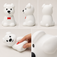Différents angles de vue, texture souple en silicone et détails de la veilleuse en forme de petit chien avec un nœud papillon rouge.
