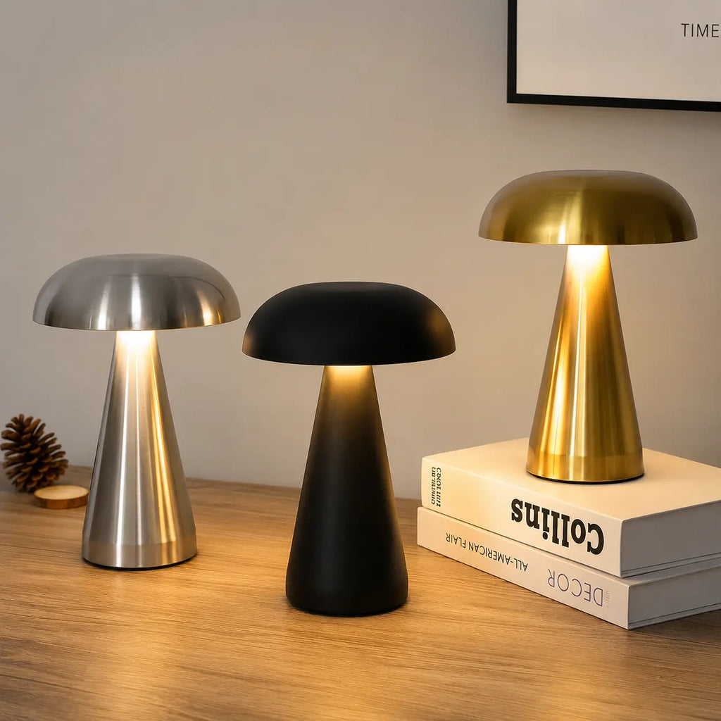 Trois veilleuses de table champignon allumées en finition argentée noire et dorée posées sur une table en bois