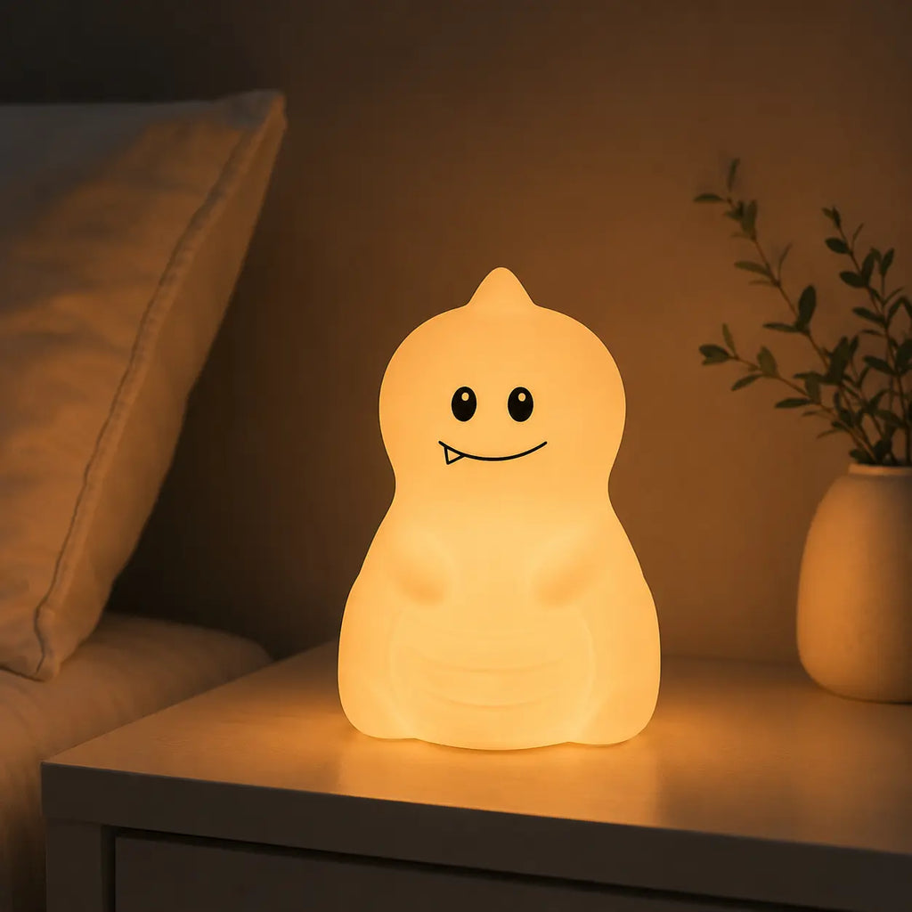 Veilleuse en forme de petit dinosaure allumée posée sur une table de chevet dans une ambiance chaleureuse.