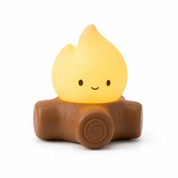 Veilleuse en forme de feu de camp avec une flamme jaune souriante posée sur des bûches de bois sur fond blanc