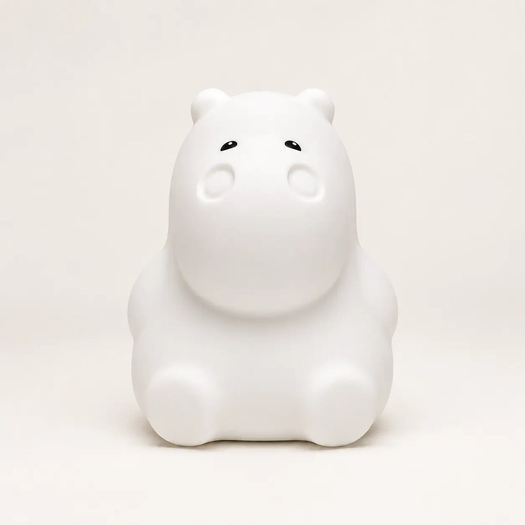 Veilleuse en silicone en forme de petit hippopotame blanc, sur un fond beige neutre.
