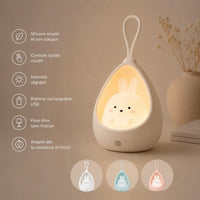 Infographie en français présentant une veilleuse lapin cocon blanche allumée sur fond beige, détaillant ses caractéristiques (silicone souple, contrôle tactile, intensité réglable, batterie USB, pose libre, dès la naissance) avec trois vignettes montrant les déclinaisons de couleurs.