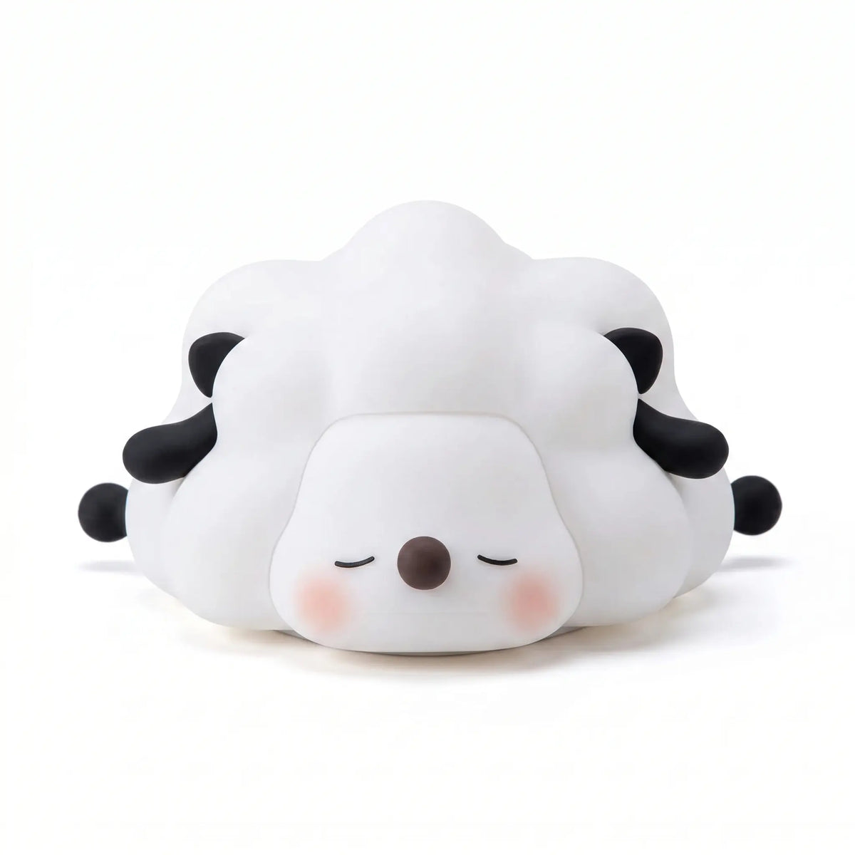 Veilleuse en silicone en forme de petit mouton blanc et noir couché aux yeux fermés, sur un fond blanc.