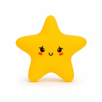 Veilleuse en silicone en forme de petite étoile jaune aux bords arrondis. Elle présente un visage de style kawaii dessiné de face avec de grands yeux expressifs aux reflets blancs, de petites joues rouges et un sourire timide, le tout présenté sur un fond blanc épuré.