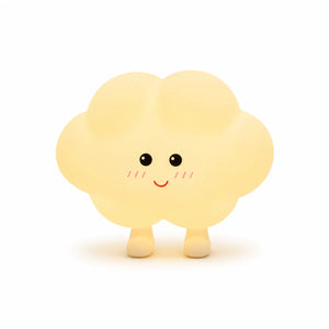 Veilleuse en silicone en forme de petit nuage jaune pâle tout rond doté de deux petits pieds. Elle présente un visage joyeux de style kawaii dessiné de face avec des yeux ronds noirs, de petites pommettes rosées et un grand sourire rouge, présentée sur un fond blanc épuré.