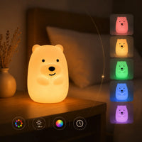 Veilleuse en forme de petit ours allumée sur une table de chevet, avec des miniatures montrant ses différentes déclinaisons de couleurs lumineuses.