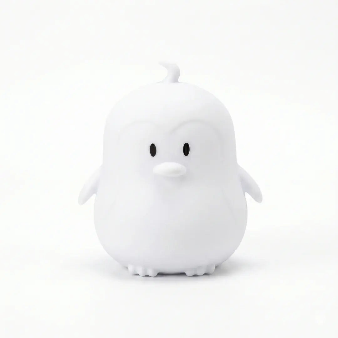 Veilleuse en silicone en forme de petit pingouin blanc sur fond blanc.