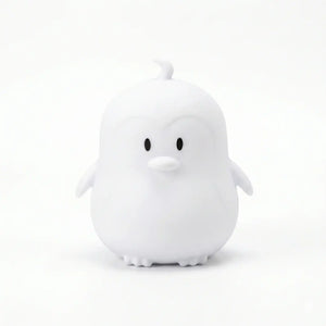Veilleuse en silicone en forme de petit pingouin blanc sur fond blanc.